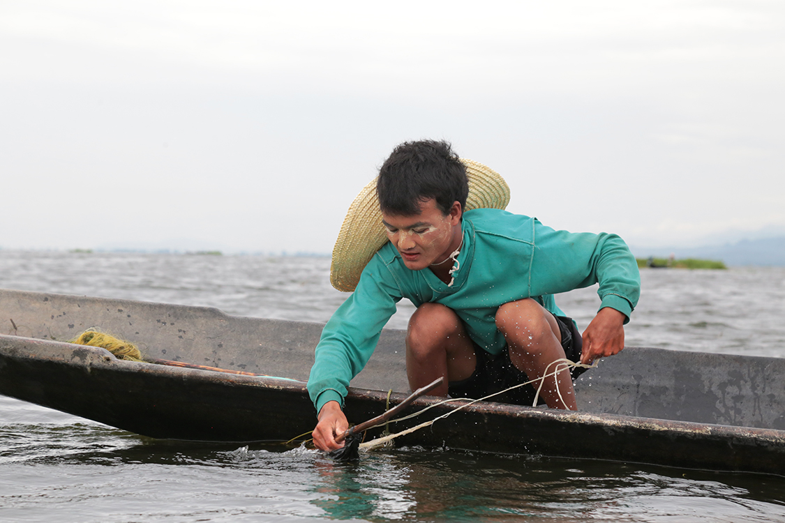 Lac Inle.
Notre guide, souhaitant acheter du poisson pour sa maman, a accostÃ© ce jeune pÃªcheur pour voir ses prises qu'il garde dans un filet dans l'eau.